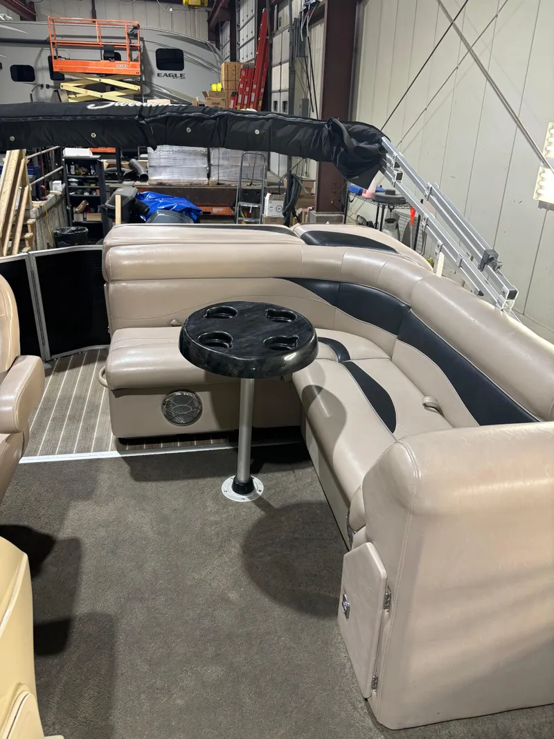 Slide: The Image of 2015 Godfrey Sweetwater 2286 pontoon boat interior with beige seating and a round table. - 6