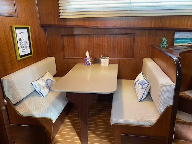 Slide: The Image of Cozy dining nook in 1973 Hatteras Motor Yacht with wood paneling and cushioned seating. - 10