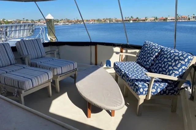 Slide: The Image of 1973 Hatteras Motor Yacht deck with striped and patterned seating, overlooking serene waterfront. - 19