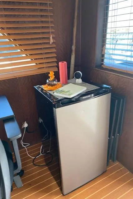 Slide: The Image of Mini fridge in 1973 Hatteras Motor Yacht interior with wooden blinds and desk. - 23