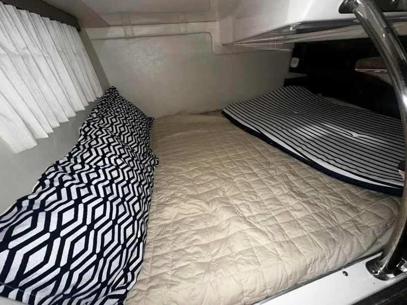 Slide: The Image of Cozy cabin interior of 2018 Regal 28 Express with patterned pillows and striped bedding. - 2