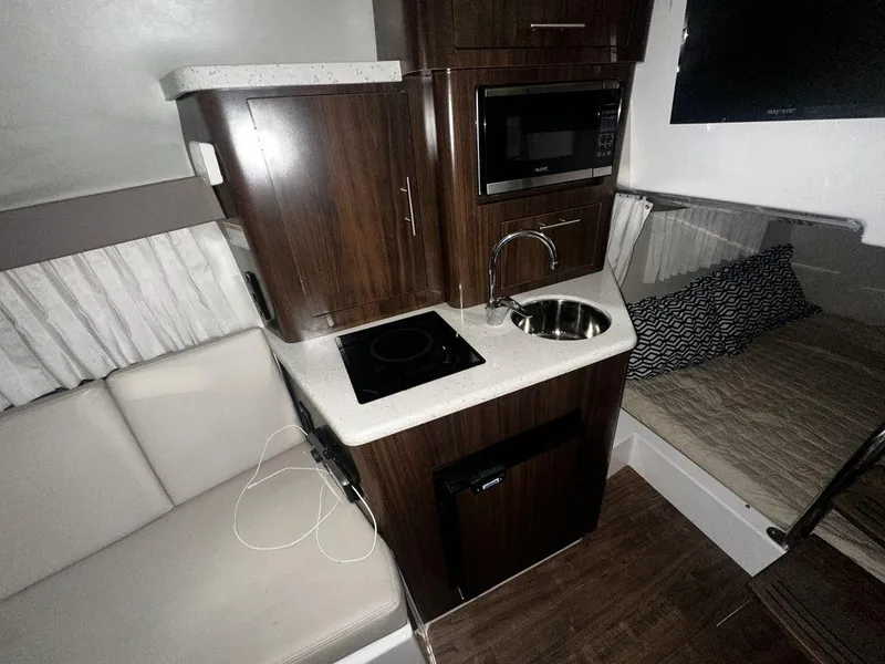 Slide: The Image of 2018 Regal 28 Express boat interior with kitchenette, sink, and seating area. - 3