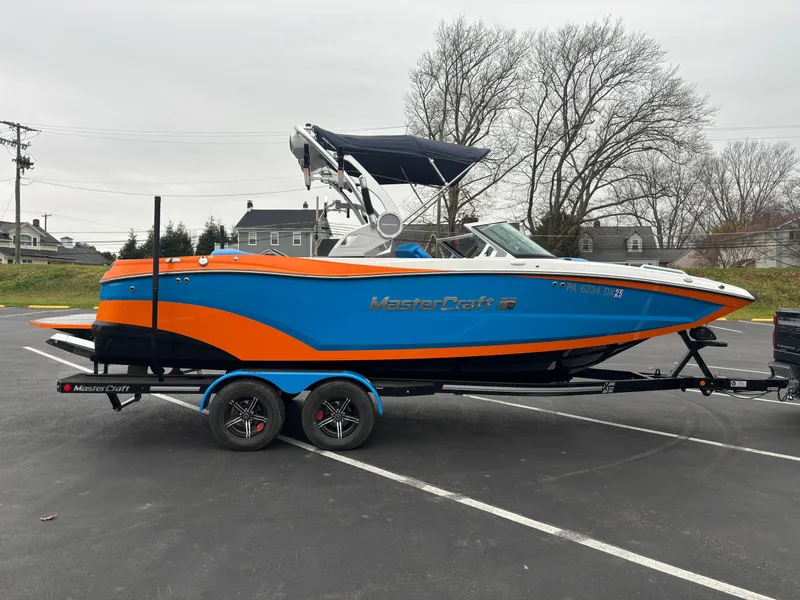 Slide: The Image of 2020 MasterCraft XT22 boat in blue and orange on a trailer in a parking lot. - 11