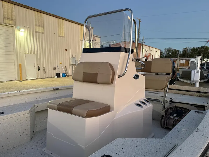 Slide: The Image of 2020 Xpress H20B boat with beige seating and console, docked near industrial buildings. - 2