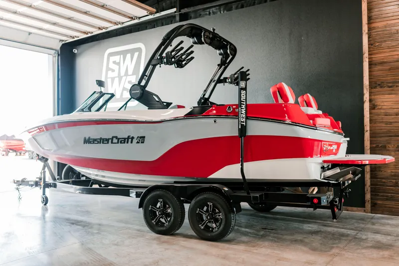 Slide: The Image of 2025 MasterCraft XT22 boat in red and white, displayed indoors on a trailer. - 1