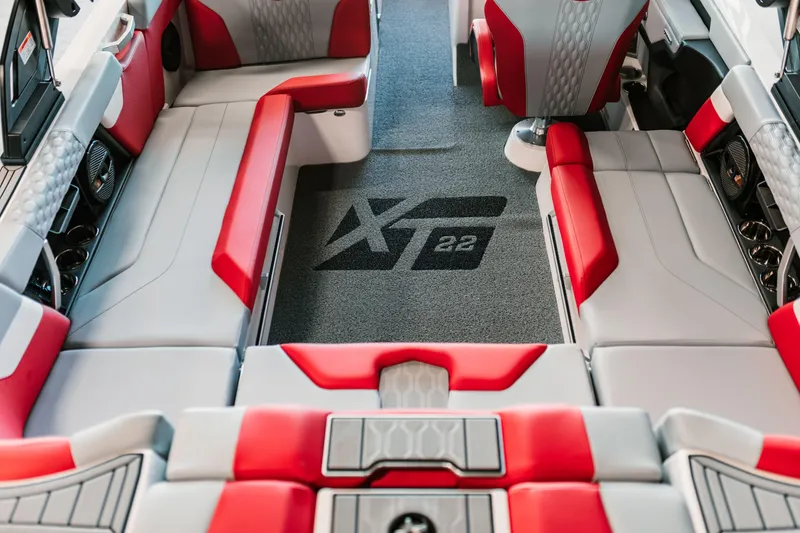 Slide: The Image of 2025 MasterCraft XT22 interior with red and gray seating, featuring logo on carpet. - 7