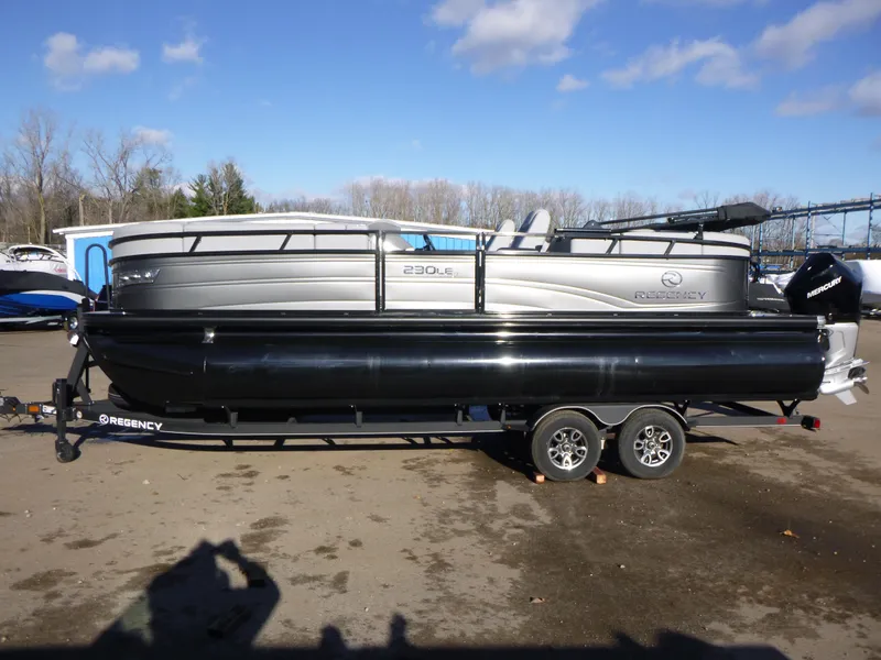 Slide: The Image of 2025 Regency 230 LE3 pontoon boat on trailer, parked outdoors. - 1
