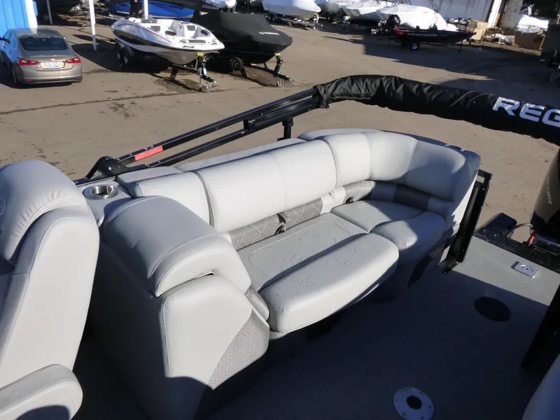 Slide: The Image of 2025 Regency 230 LE3 pontoon boat with gray seating, docked outdoors. - 18
