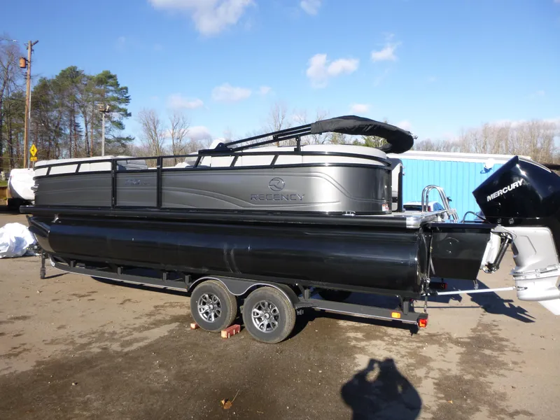 Slide: The Image of 2025 Regency 230 LE3 pontoon boat on trailer, parked outdoors. - 2