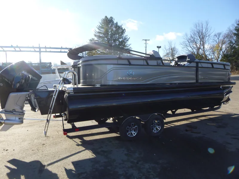 Slide: The Image of 2025 Regency 230 LE3 pontoon boat on trailer, parked outdoors. - 7
