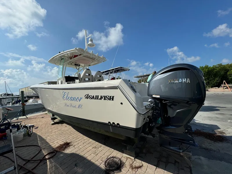 Slide: The Image of 2023 Sailfish 290cc boat with Yamaha engine, docked under a clear blue sky. - 1