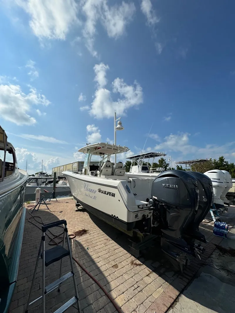 Slide: The Image of 2023 Sailfish 290cc boat docked under a clear blue sky. - 2