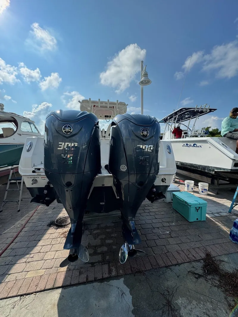 Slide: The Image of 2023 Sailfish 290cc boat with dual outboard engines, docked under a clear blue sky. - 6
