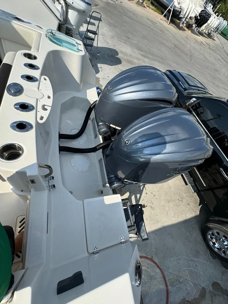 Slide: The Image of 2023 Sailfish 290cc boat with dual outboard motors, docked near a black vehicle. - 7