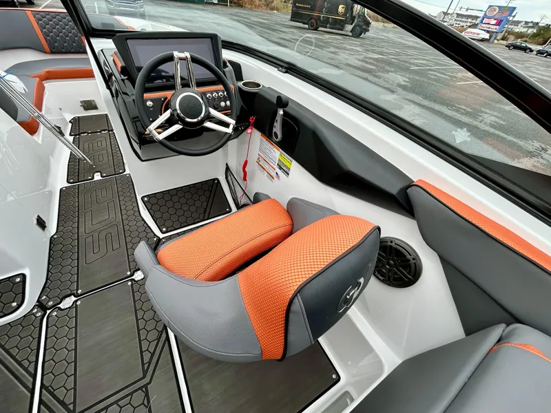 Slide: The Image of 2025 Scarab 255LX boat interior with orange and gray seating, modern steering console. - 10