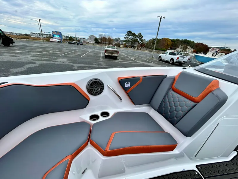 Slide: The Image of 2025 Scarab 255LX boat interior with gray and orange seating in a parking lot. - 12