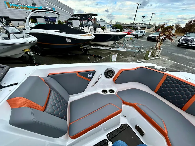 Slide: The Image of 2025 Scarab 255LX boat interior with gray and orange seating, displayed in a marina. - 15