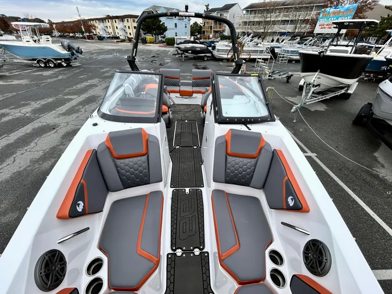 Slide: The Image of 2025 Scarab 255LX boat interior with gray and orange seating, docked at a marina. - 16
