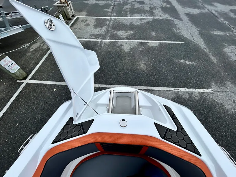 Slide: The Image of 2025 Scarab 255LX boat with open storage compartment, orange and black seating. - 20