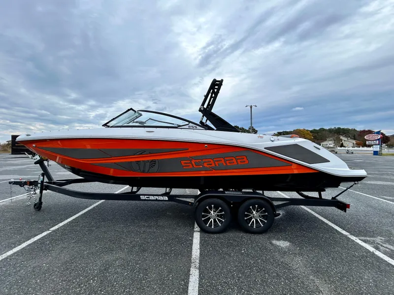 Slide: The Image of 2025 Scarab 255LX boat on trailer, featuring sleek design and vibrant orange accents. - 4