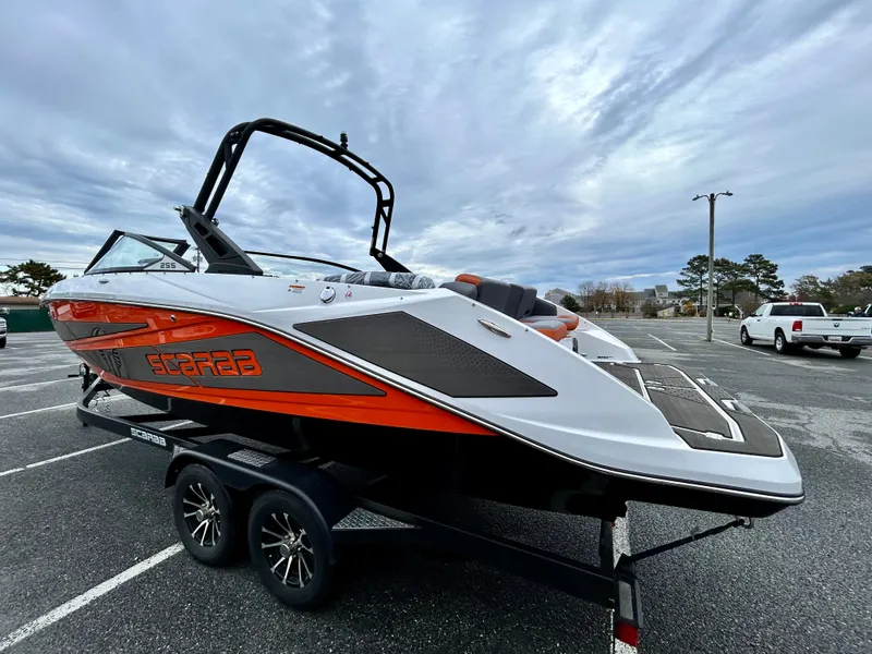 Slide: The Image of 2025 Scarab 255LX boat on trailer, sleek design, vibrant orange accents, parked outdoors. - 5