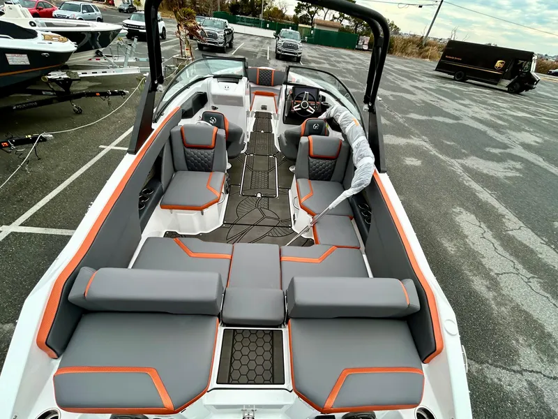 Slide: The Image of 2025 Scarab 255LX boat with gray and orange seating, parked in a lot. - 9
