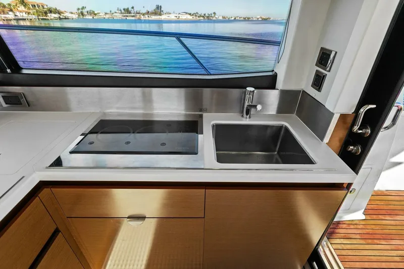 Slide: The Image of Prestige 450 S 2014 yacht kitchen with sink and stove, overlooking scenic water view. - 16