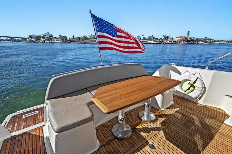 Slide: The Image of Prestige 450 S yacht deck with American flag, wooden table, and waterfront view. - 7