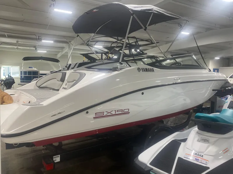 Slide: The Image of 2024 Yamaha Boats SX190 in showroom, sleek white design with canopy. - 1