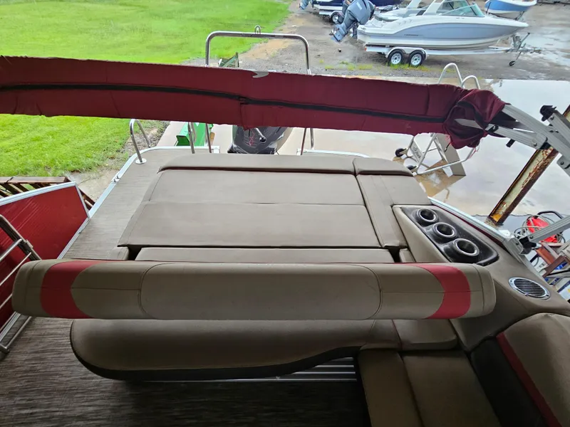 Slide: The Image of 2021 Bennington 22 SX pontoon boat interior with seating and cup holders, docked near other boats. - 23