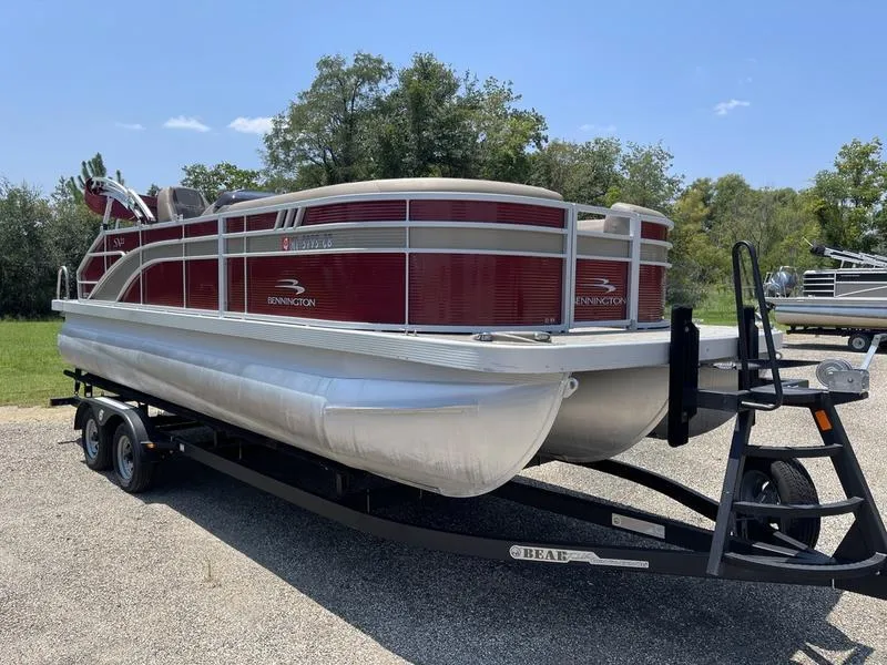 Slide: The Image of 2021 Bennington 22 SX pontoon boat on trailer, red and white design, parked outdoors. - 3