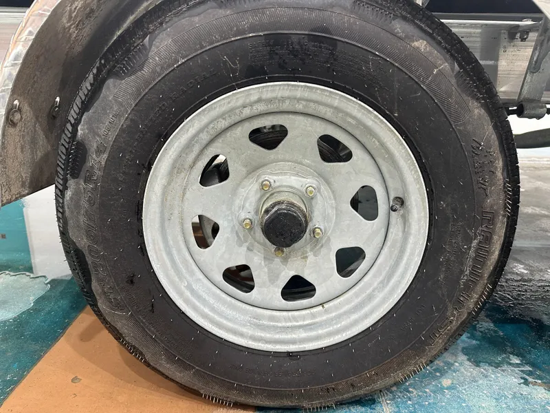 Slide: The Image of 2024 Chaparral SSI21SP trailer wheel with metal rim and black tire. - 13