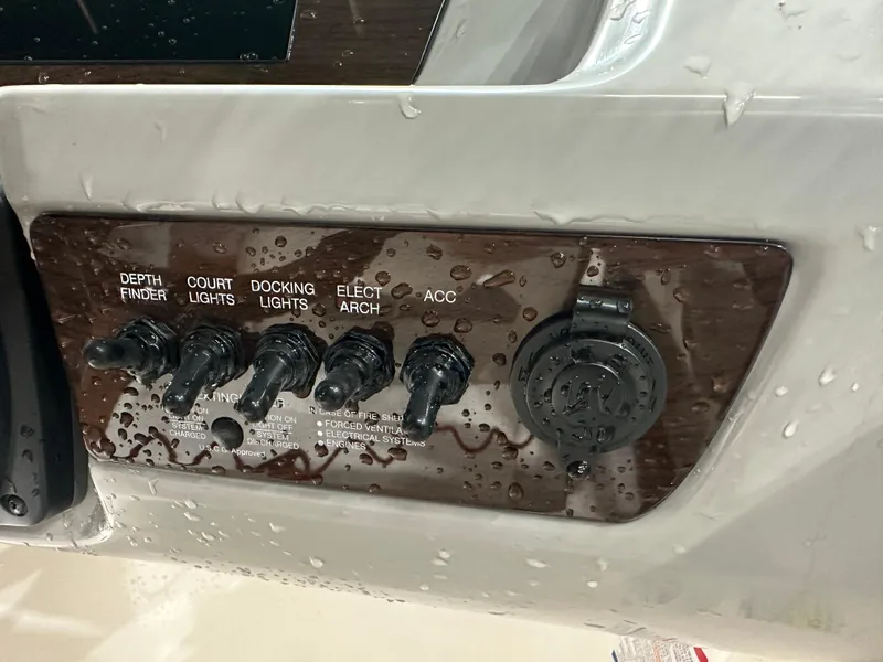 Slide: The Image of Control panel of 2024 Chaparral SSI21SP boat with switches and water droplets. - 27