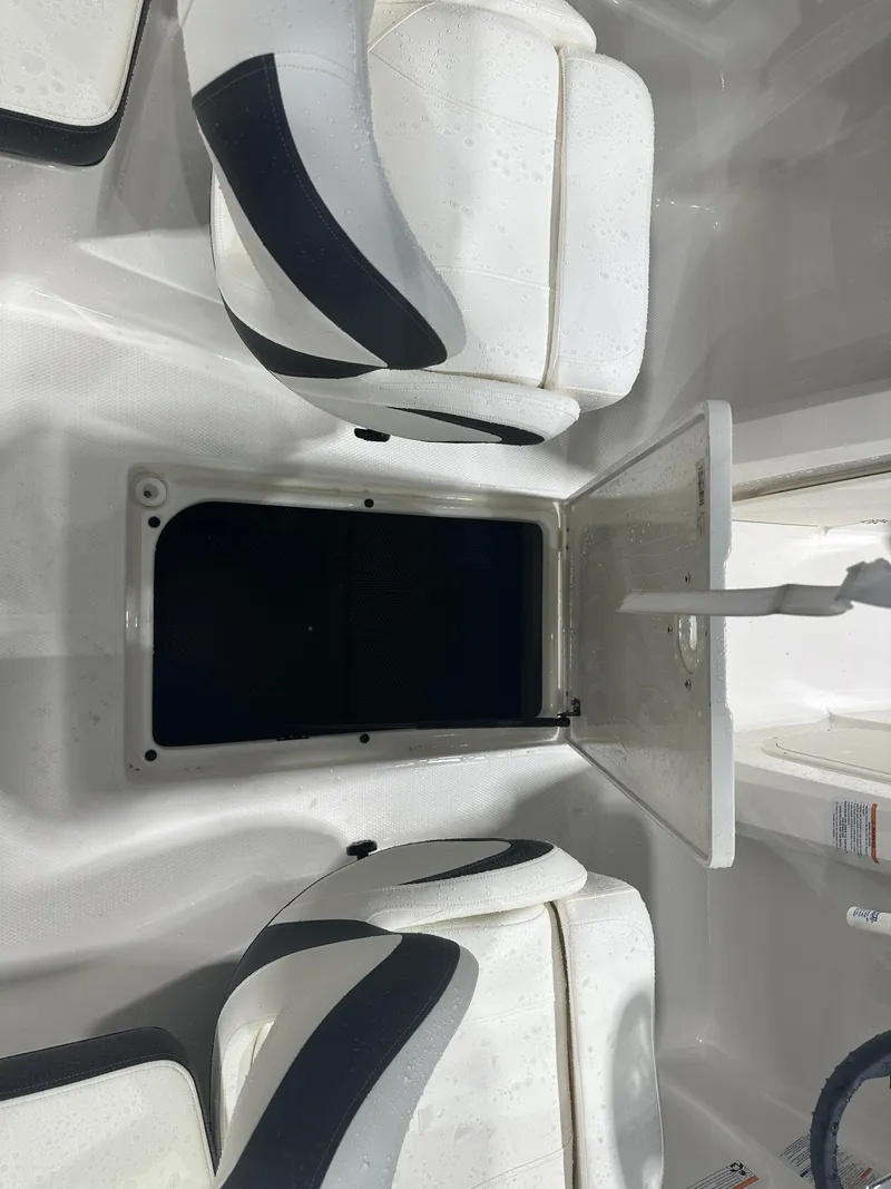 Slide: The Image of 2024 Chaparral SSI23SP boat interior with open storage compartment and cushioned seating. - 31