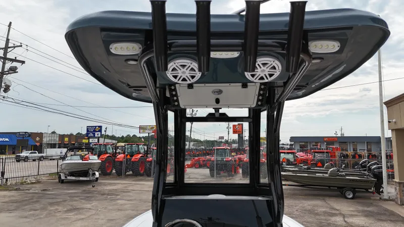 Slide: The Image of 2023 Tidewater 2410BM boat with T-top and speakers, displayed in a dealership lot. - 18