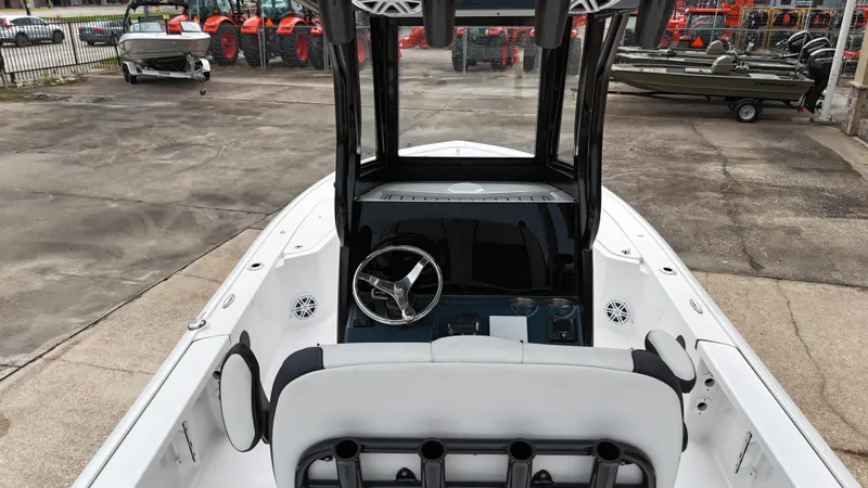 Slide: The Image of 2023 Tidewater 2410BM boat interior with steering wheel and seating, parked outdoors. - 19