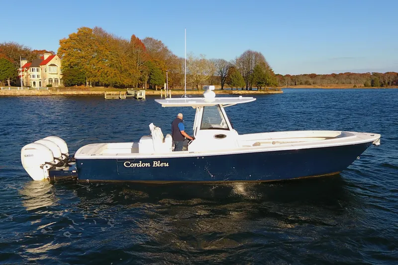 Slide: The Image of 2023 Regulator 34 boat on water, autumn trees in background. - 2