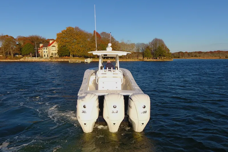 Slide: The Image of 2023 Regulator 34 boat with triple engines cruising on a scenic lake. - 4