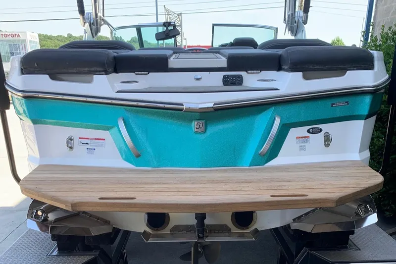 Slide: The Image of 2018 MasterCraft XT22 boat with teal and white exterior, rear view. - 3