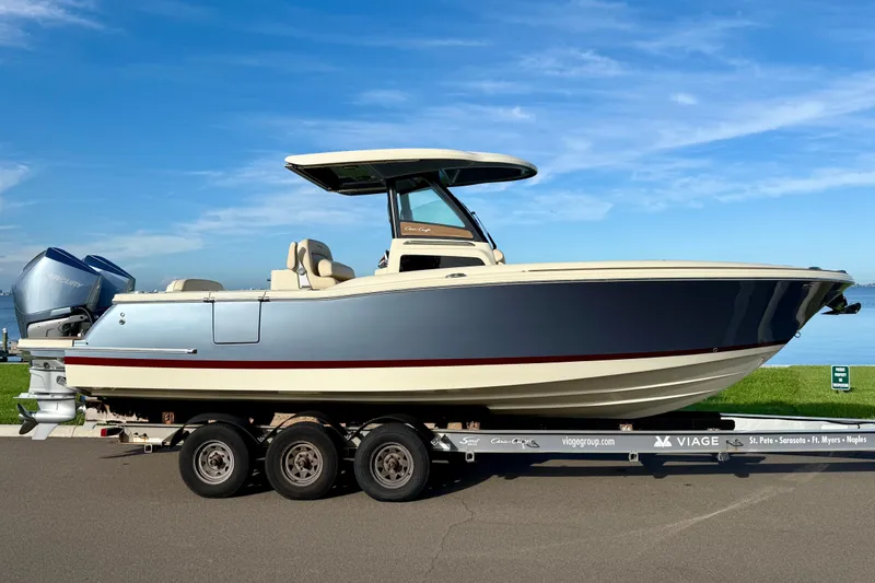 Slide: The Image of 2025 Chris-Craft Catalina 28 boat on trailer, parked by waterfront under clear blue sky. - 3