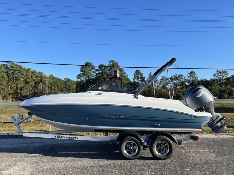 Slide: The Image of 2025 Stingray 201DC boat on trailer, blue and white design, parked outdoors. - 1