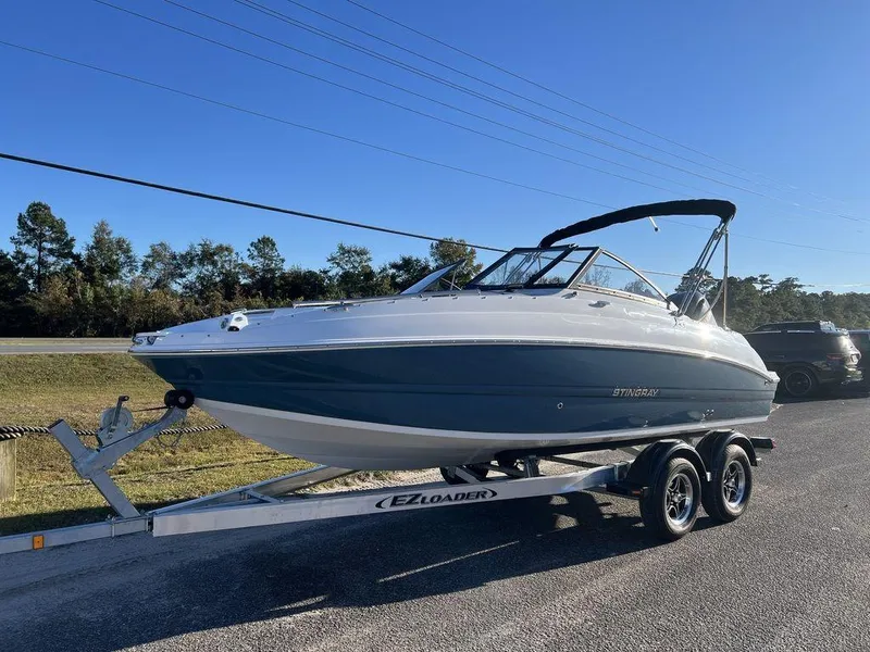 Slide: The Image of 2025 Stingray 201DC boat on trailer, parked outdoors under clear blue sky. - 2