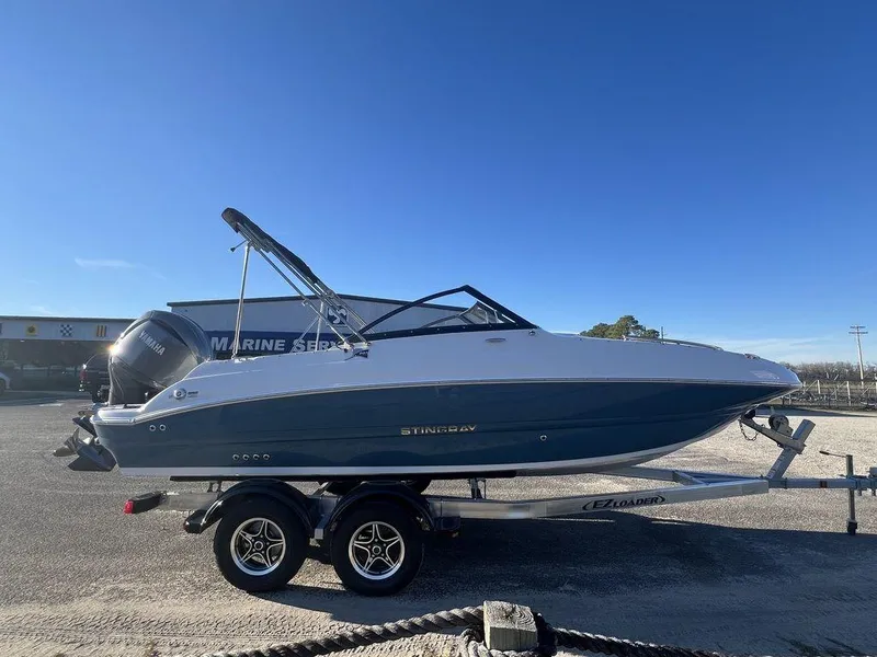 Slide: The Image of 2025 Stingray 201DC boat on trailer, parked outdoors under clear blue sky. - 4