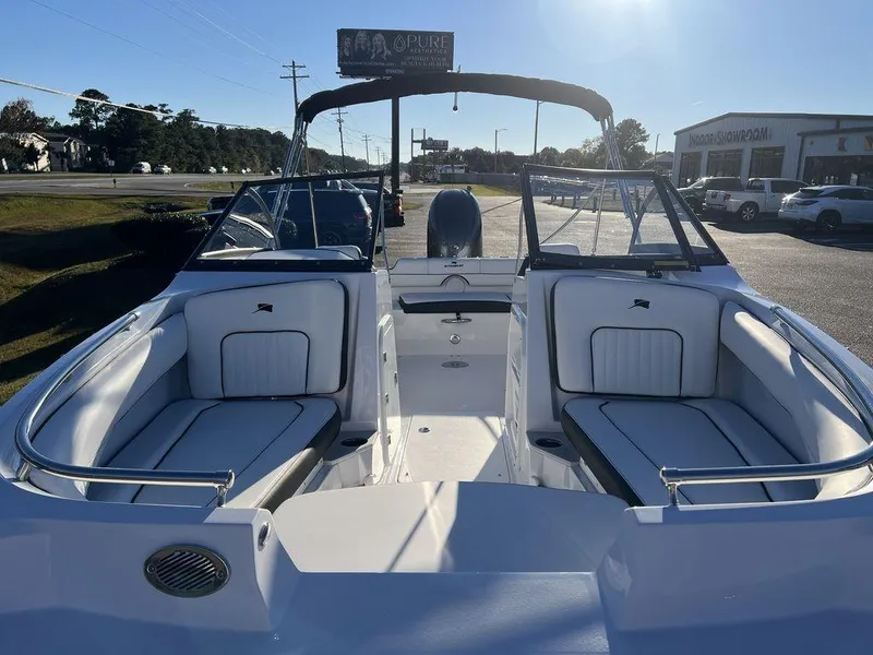 Slide: The Image of 2025 Stingray 201DC boat interior with white seating and open deck, parked outdoors. - 5