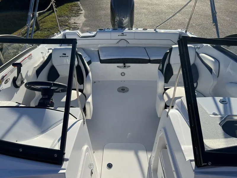 Slide: The Image of 2025 Stingray 201DC boat interior with seating and steering wheel, docked in sunlight. - 6