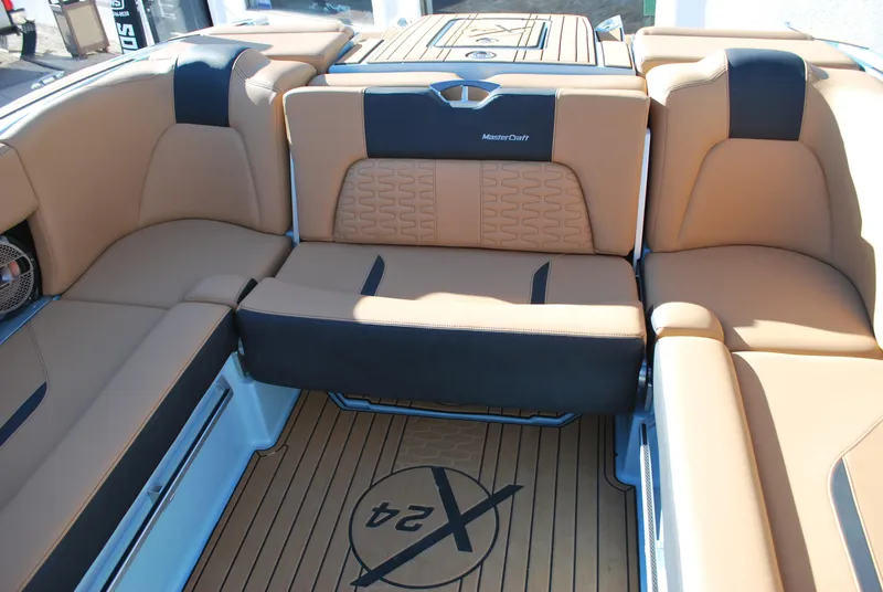Slide: The Image of 2022 MasterCraft X24 boat interior with tan and black seating, featuring logo on deck. - 12
