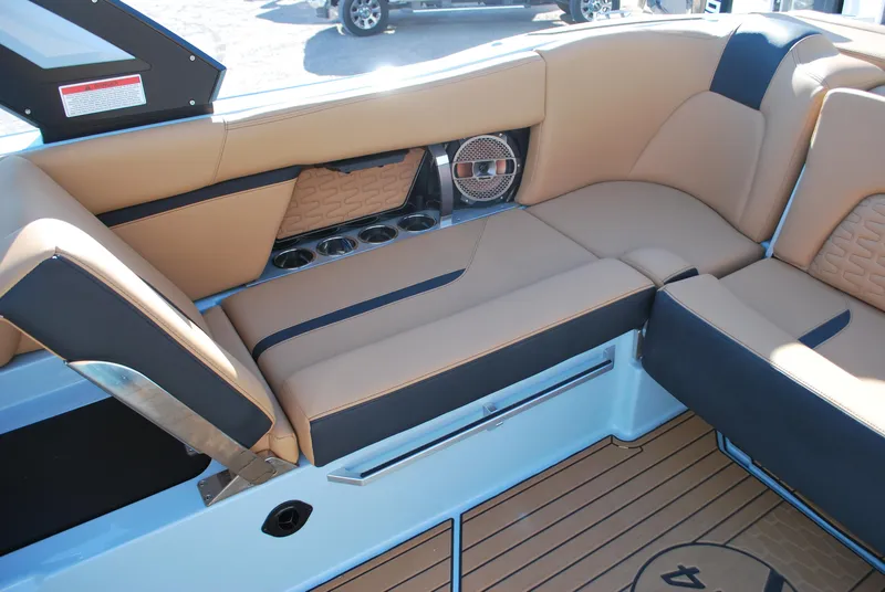 Slide: The Image of 2022 MasterCraft X24 boat interior with tan and black seating, cup holders, and speaker. - 13