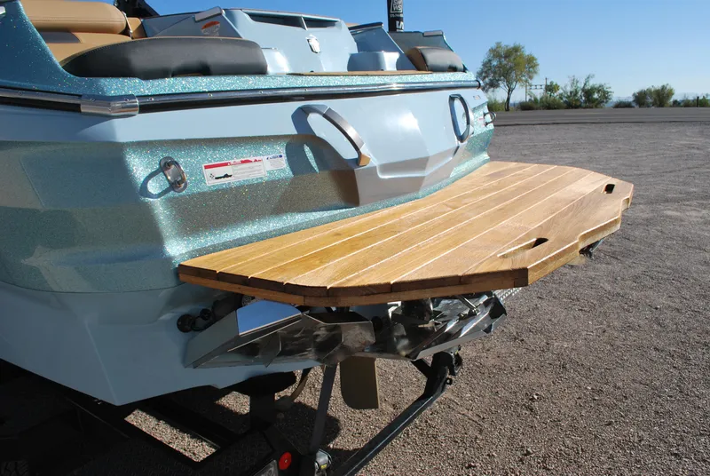 Slide: The Image of 2022 MasterCraft X24 boat with wooden swim platform in a sunny outdoor setting. - 19