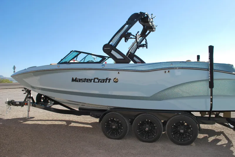 Slide: The Image of 2022 MasterCraft X24 boat on trailer under clear blue sky. - 2