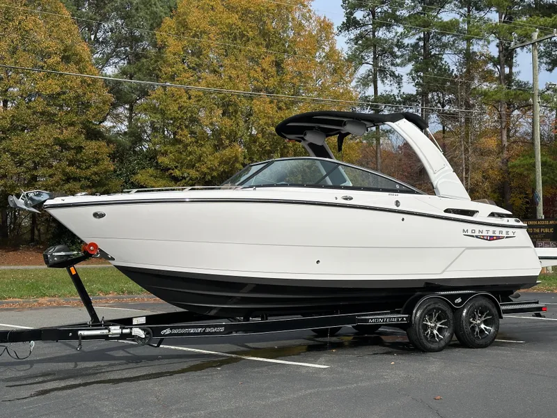 Slide: The Image of 2025 Monterey 258SS boat on trailer, parked outdoors with trees in background. - 24